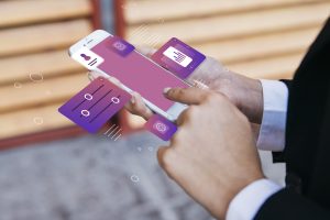Pessoa utilizando um smartphone com interface digital futurista, exibindo ícones flutuantes relacionados a gráficos, configurações e segurança. A cena representa a inovação no setor financeiro, destacando o uso de cartões de crédito digitais, que proporcionam praticidade, segurança e controle na gestão de pagamentos por meio de aplicativos e plataformas online, revolucionando a experiência do consumidor.