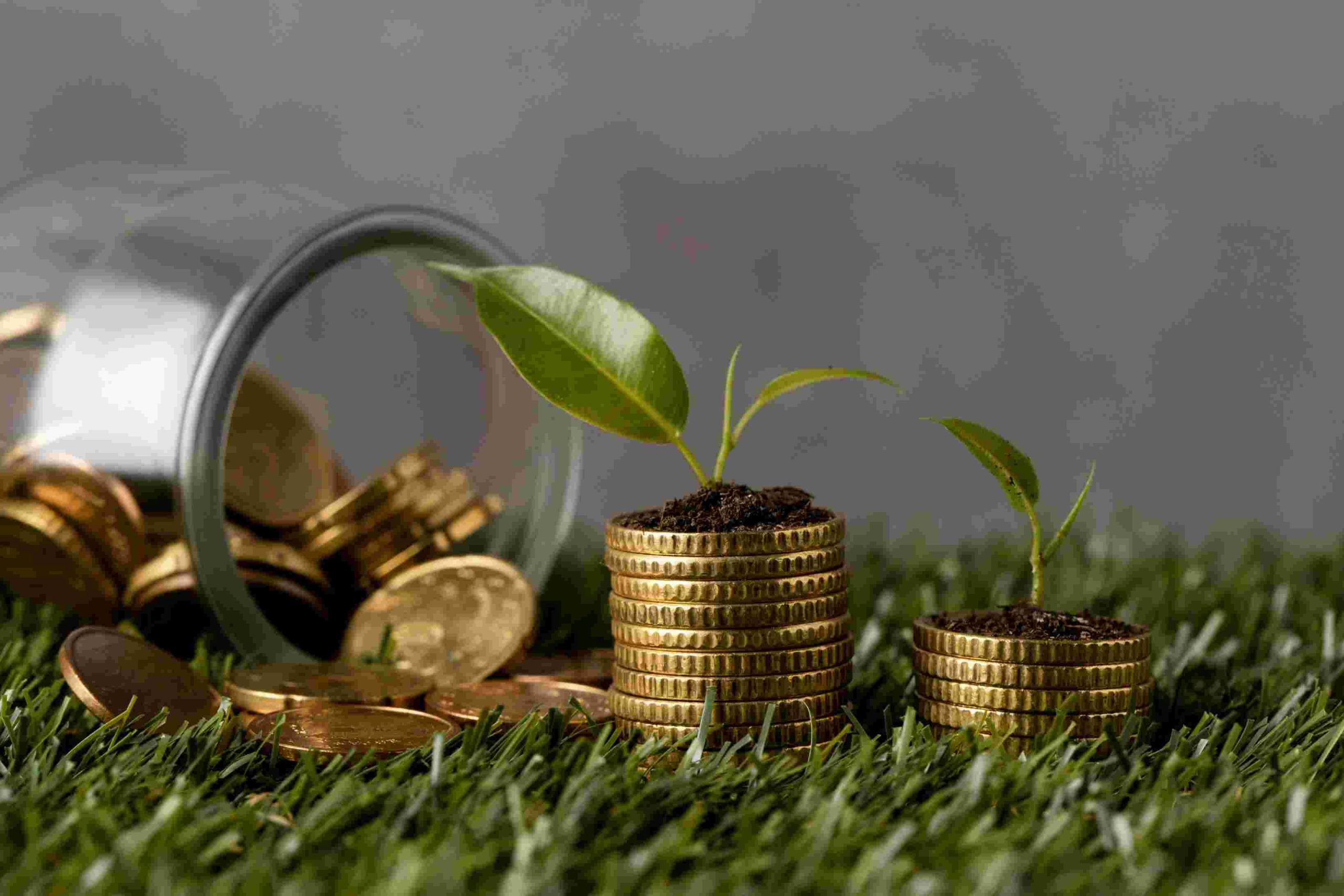 Moedas empilhadas no gramado com pequenas mudas verdes crescendo sobre elas, ao lado de um pote de vidro derramando moedas, simbolizando investimentos sustentáveis e a importância dos fundos ESG para unir retorno financeiro e responsabilidade ambiental.
